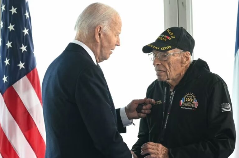 Normandia. I veterani del D-Day su sedia a rotelle sul palco del cimitero americano. L’incontro con Biden